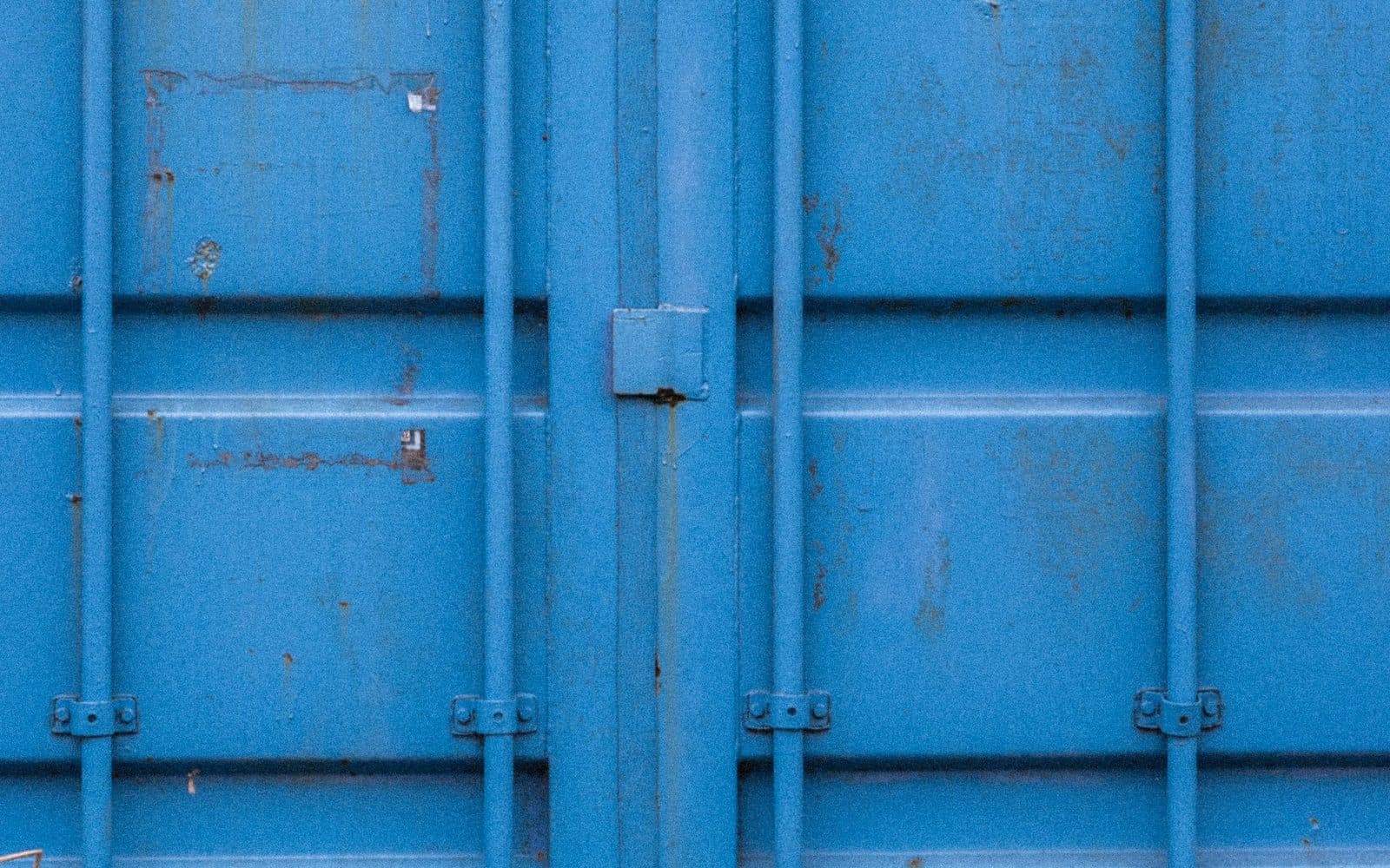 Porte de conteneur bleue marquée par l'usage, barres de verrouillage et joints